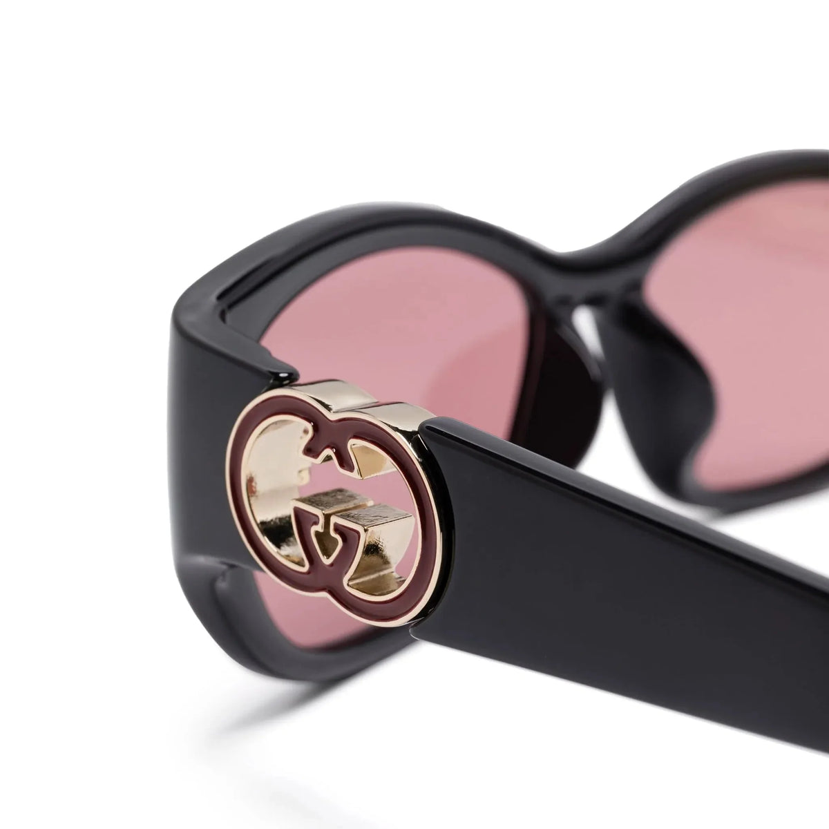 Close-up of black luxury sunglasses featuring a gold interlocking G logo on the temple.