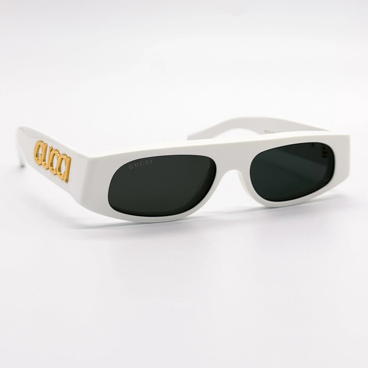 White rectangular luxury sunglasses with gold Gucci logo on the temple